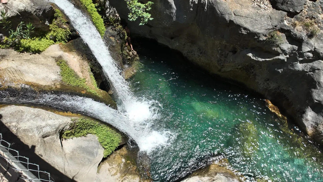 Wasser, das über moosbedeckten Fels in ein tiefes smaragdgrünes Becken im Sapadere Canyon fällt