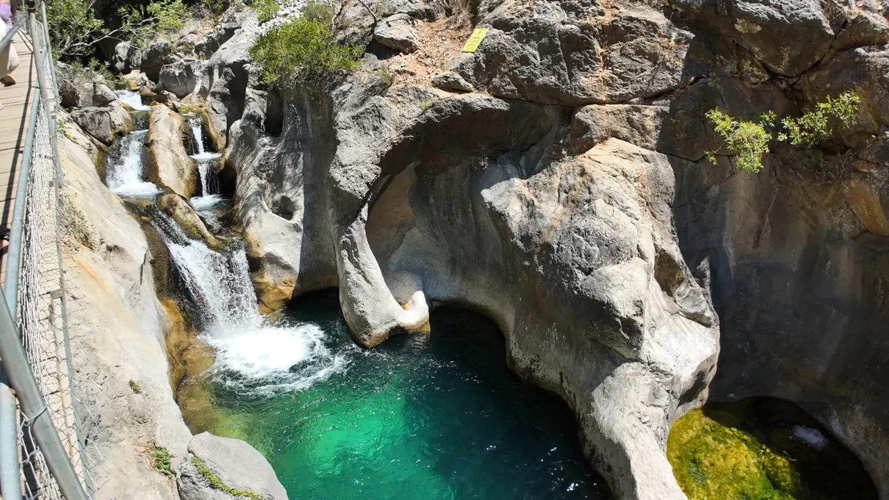Des parois calcaires sculptées par l'eau et des cascades en gradins alimentant un bassin vert profond du canyon de Sapadere