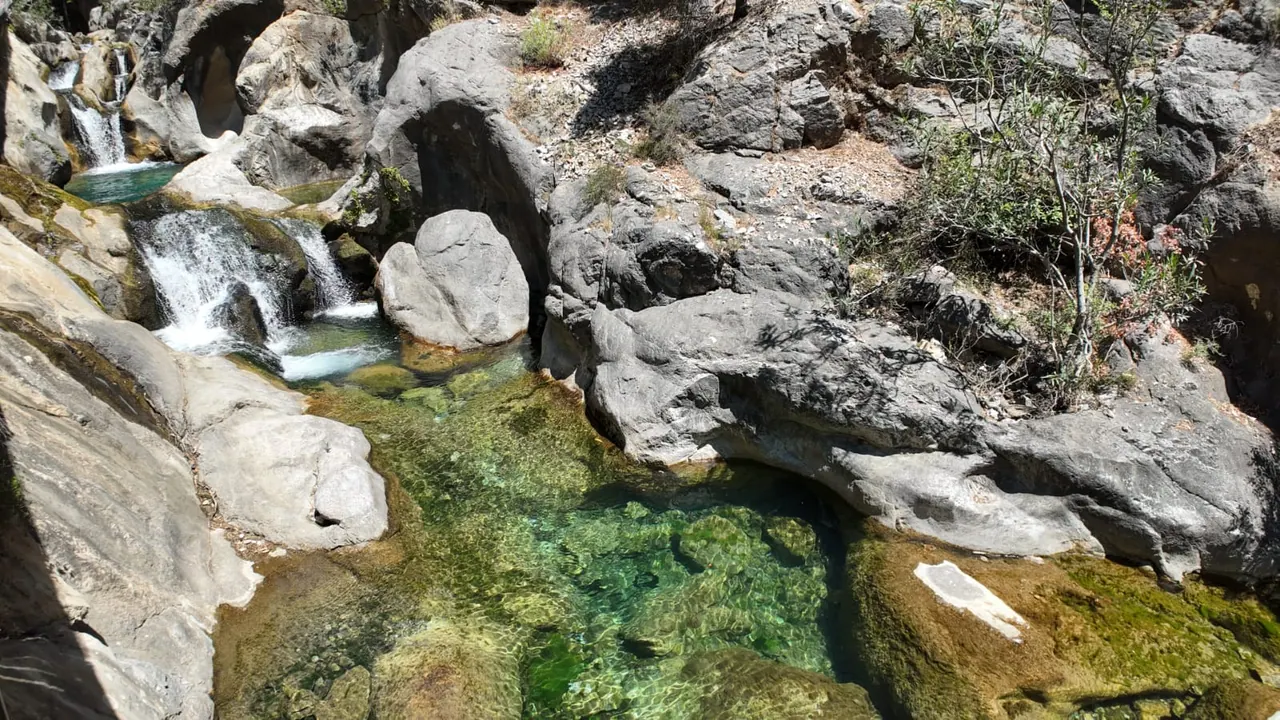 Klares flaches grünes Becken und stufige Kaskaden zwischen grauen Felsblöcken im Sapadere Canyon