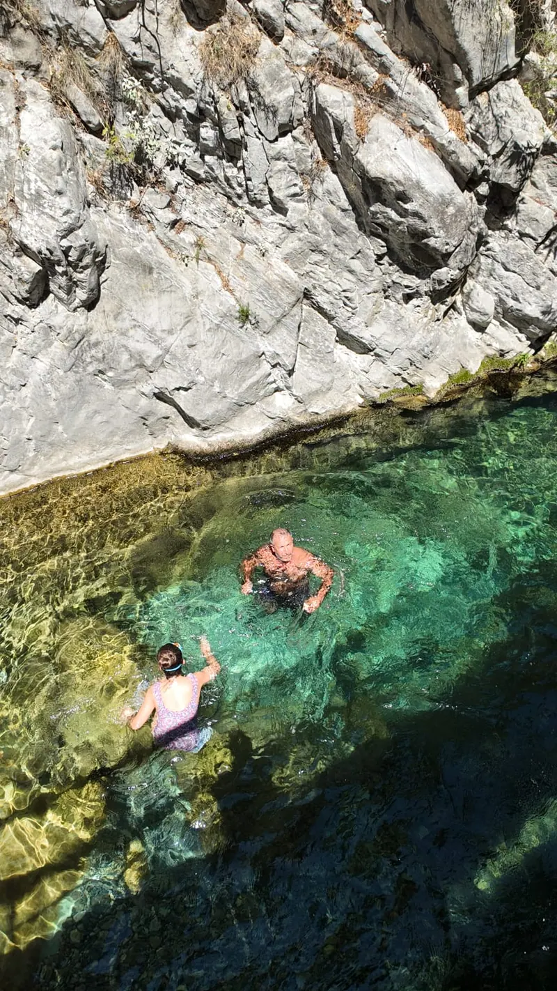 Zwei Schwimmer stehen im klaren türkisfarbenen Flussbecken unterhalb der Kalksteinwände des Sapadere Canyon