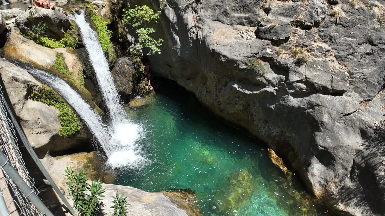 Zwei Kaskaden, die zwischen Kalksteinwänden im Sapadere Canyon in ein tiefes smaragdgrünes Becken stürzen