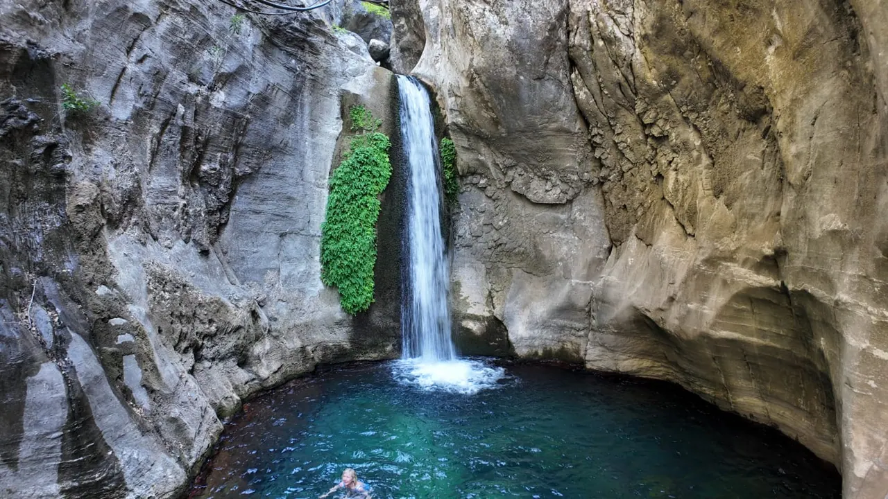 Une chute d'eau tombant dans un bassin turquoise encaissé entre les parois calcaires du canyon de Sapadere