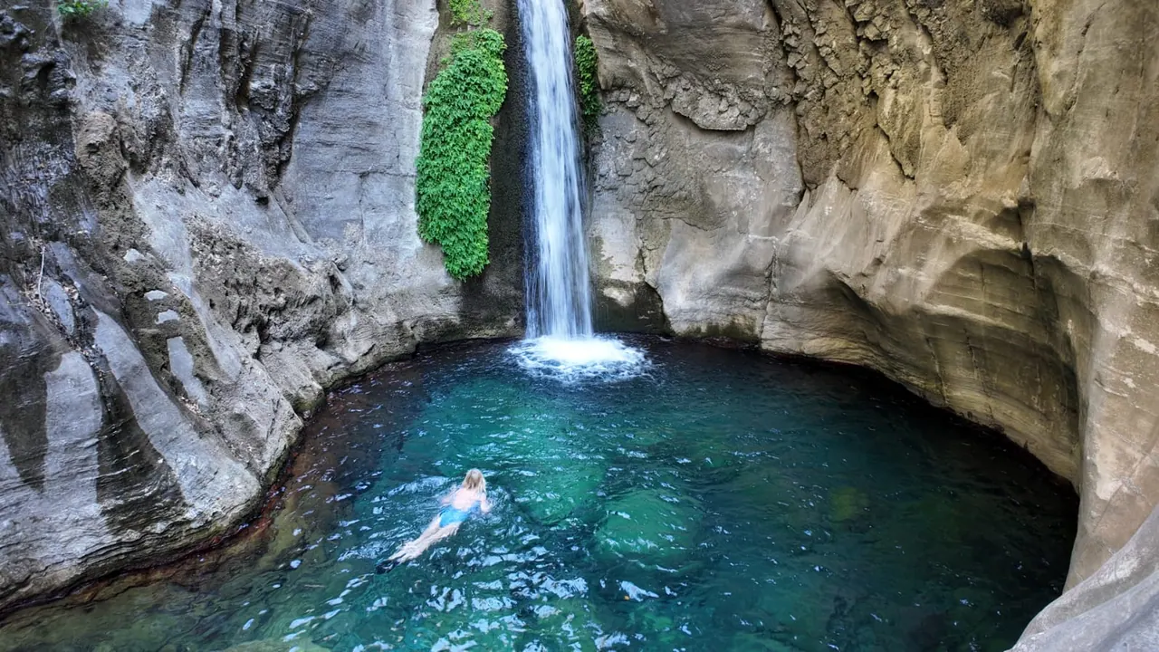 Wasserfall, der in ein smaragdgrünes Becken im Sapadere Canyon stürzt, mit einem Schwimmer im Wasser